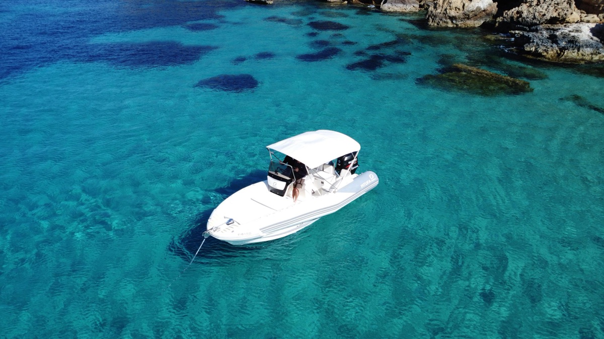 Barco Pitufa fondeado junto a los acantilados de una cala